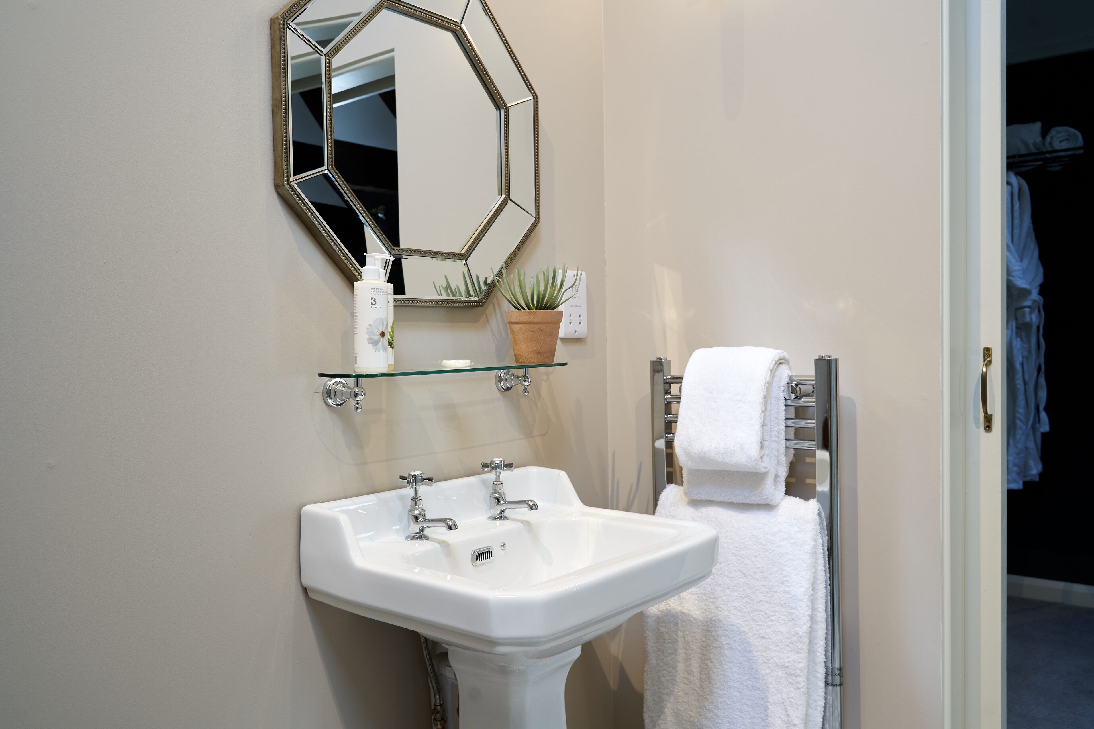 A bathroom with a white sink, a mirror, and a towel rack.