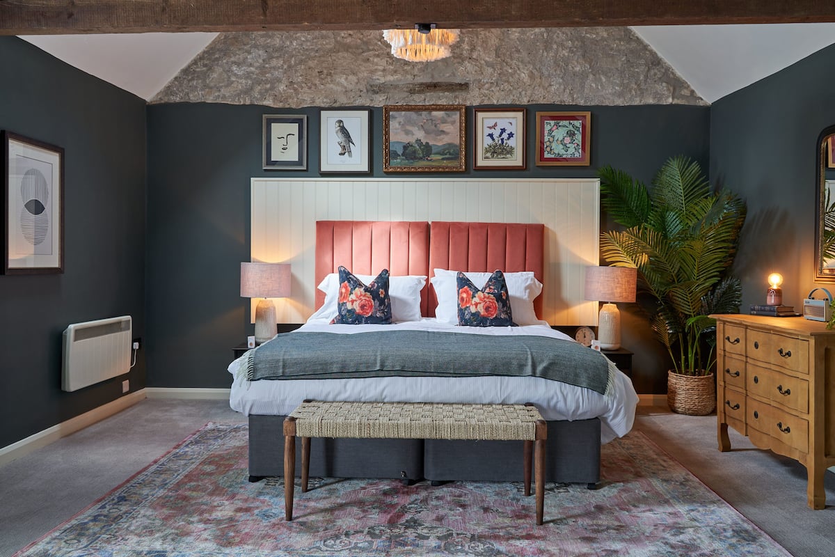 A bedroom with a large bed, a bench, a dresser, and a radiator.