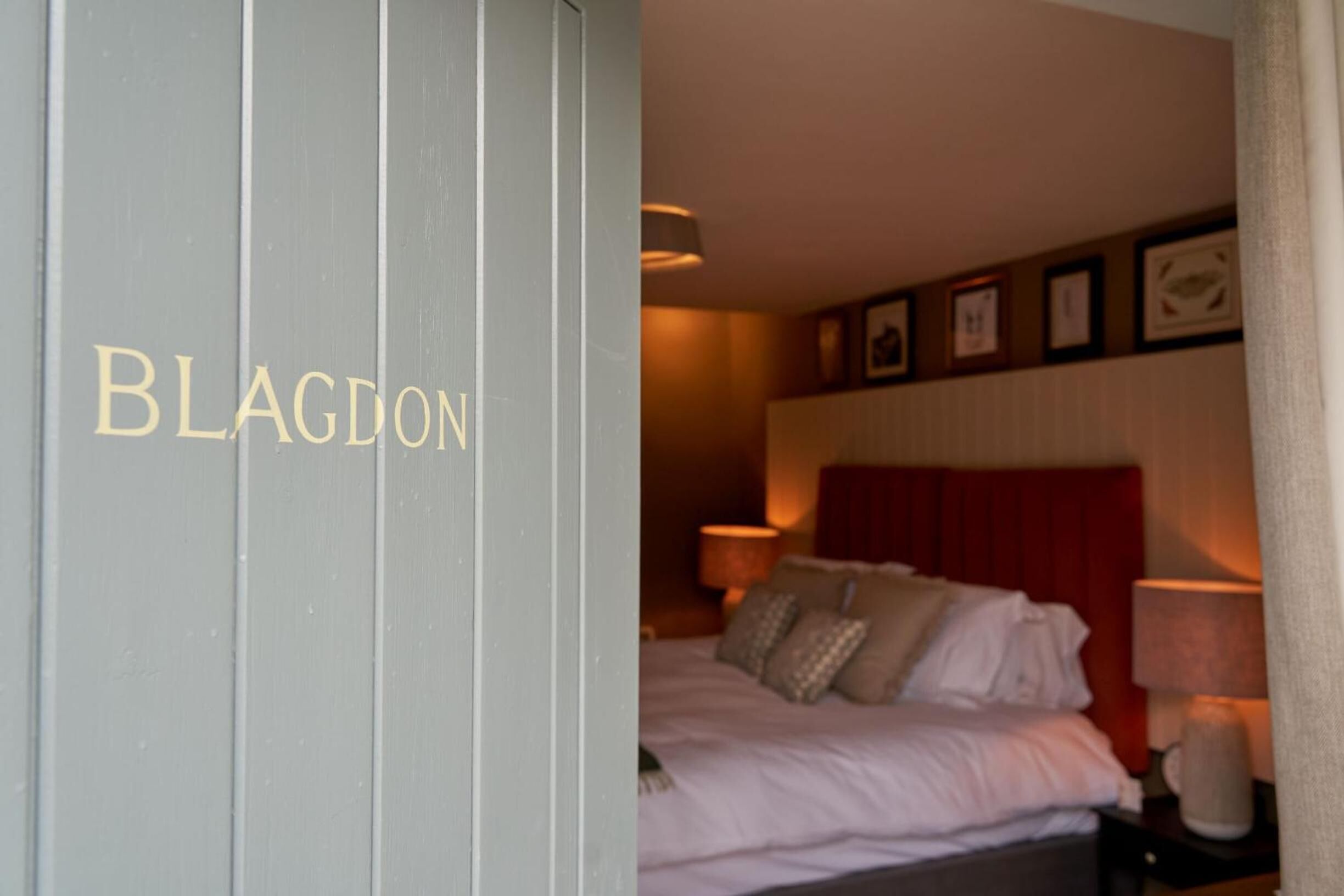 A hotel room with a bed, a nightstand, and a wall with framed pictures.