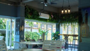 A restaurant with a blue interior, white furniture, and a view of the outside. - Nora Bukit Hotel (Phuket)