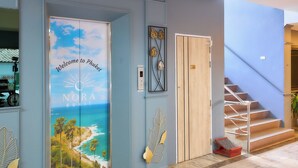 A hotel entrance with a blue wall, a decorative leaf, and a staircase. - Nora Bukit Hotel (Phuket)