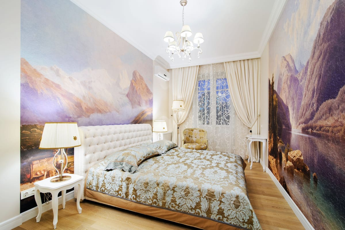 Un dormitorio con una cama grande, una araña y un mural en la pared.