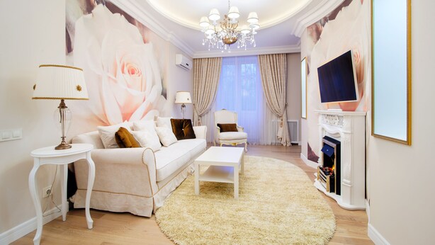 Ein Wohnzimmer mit einem weißen Sofa, einem Couchtisch, einem weißen Kamin und einem großen floralen Wandbild.