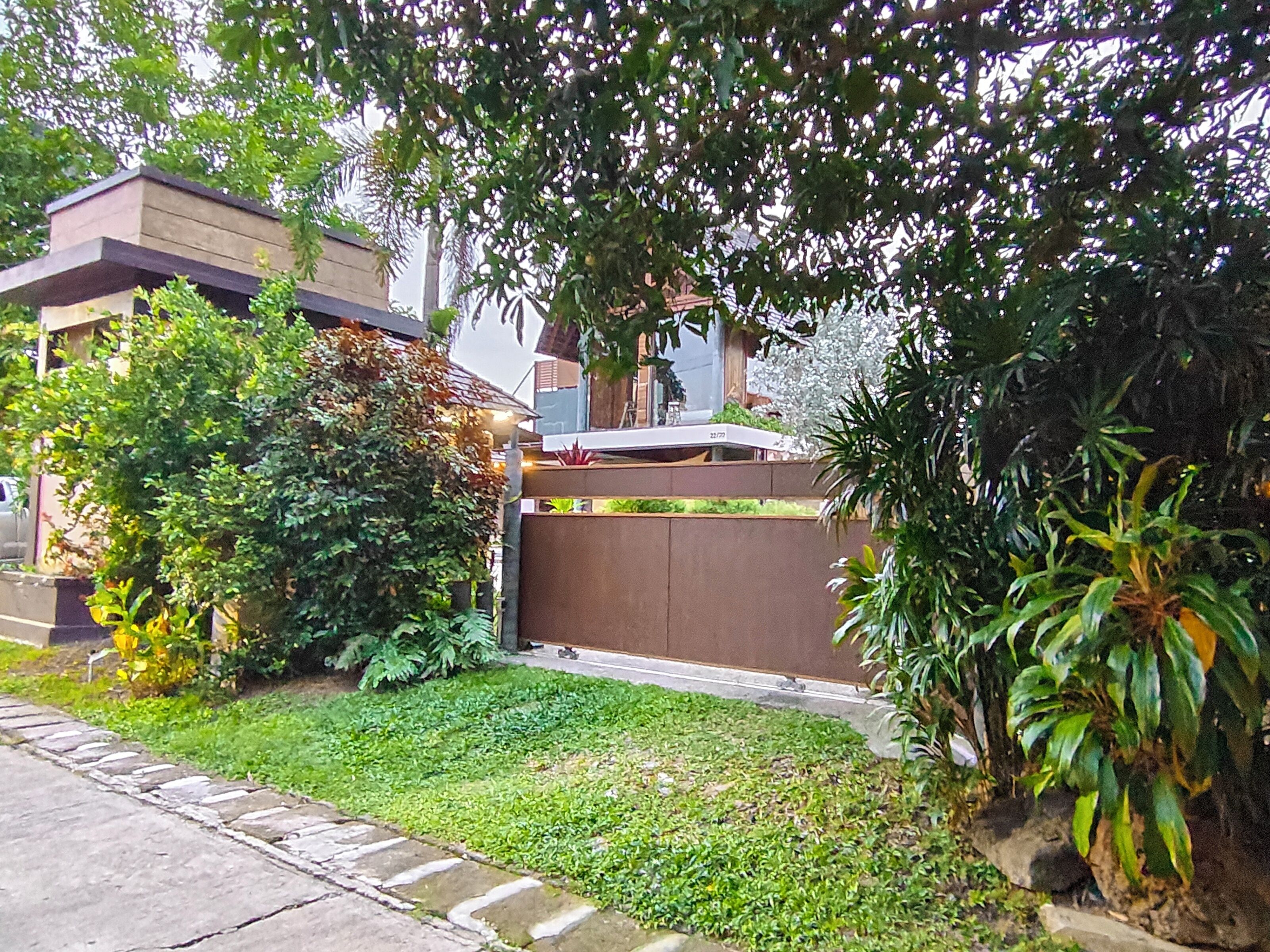 Un quartiere residenziale con un prato curato, una recinzione in legno e diverse piante.