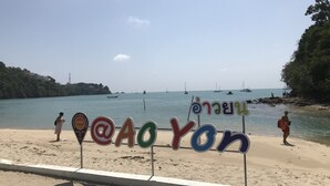 A beach with a sign spelling "AOYON" and a view of the sea with boats. - Cafe'@luv22 (Wichit)