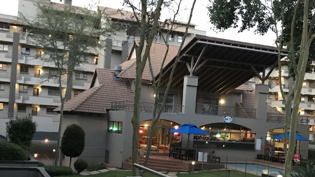 Une cour d’hôtel avec une piscine, des espaces de détente en plein air et une zone abritée.