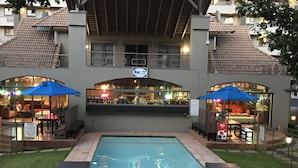 Un espace piscine agrémenté d’un panneau d’information, d’un bar et de sièges en plein air.
