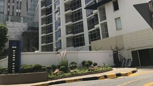 A multi-story residential building with balconies, a landscaped garden area, and a sign indicating the building's name. - First Divine Suites - Hydro Park (Sandton)
