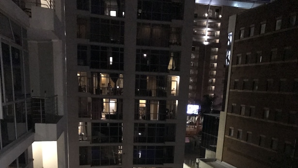 A high-rise building with multiple floors, balconies, and a pool area with blue lighting. - First Divine Suites - Hydro Park (Sandton)