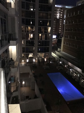 Un grattacielo con numerosi piani, balconi e un'area piscina con illuminazione blu.