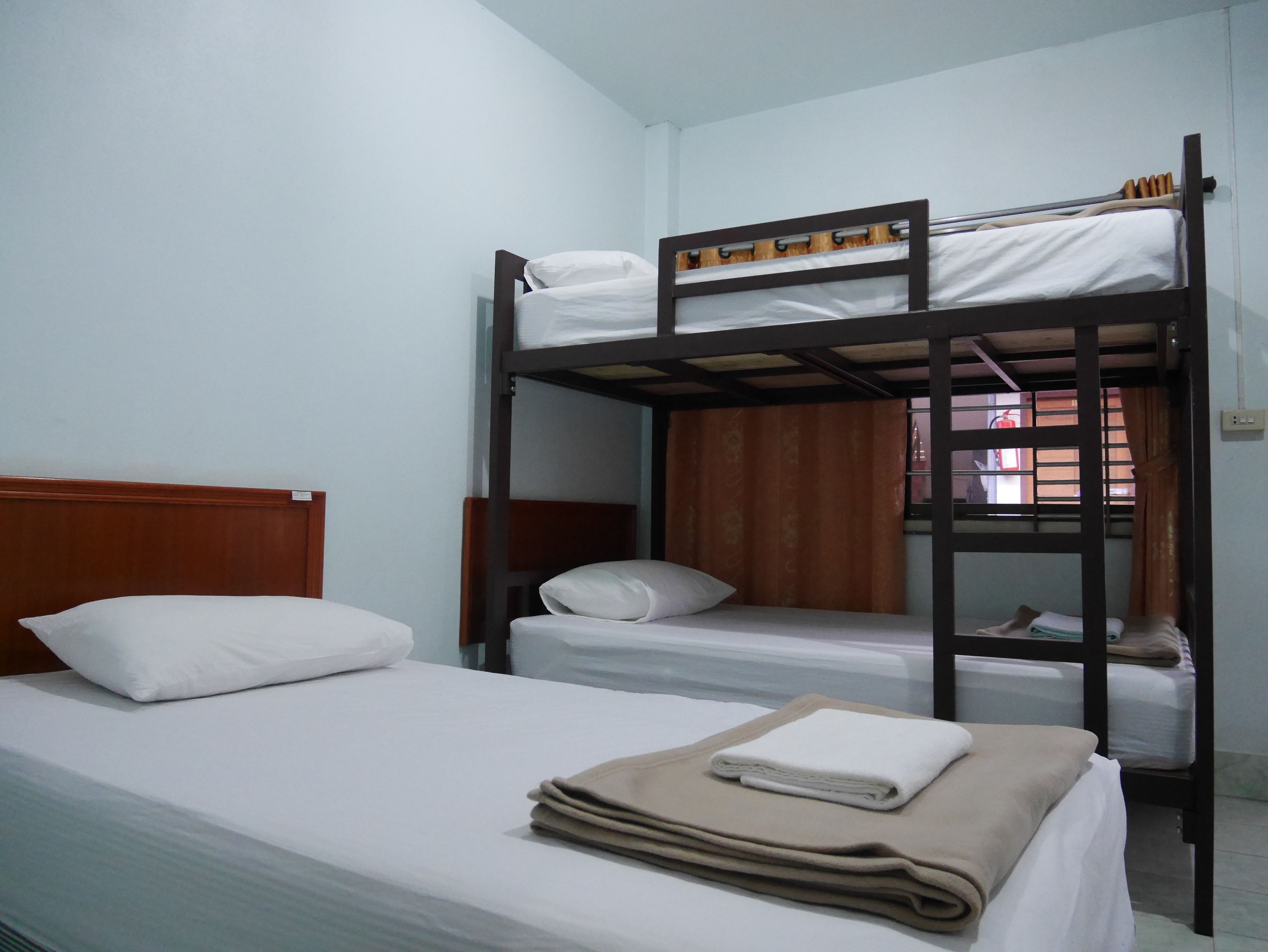 Habitación con literas, cabecera de madera, ropa de cama blanca y una ventana con cortinas.