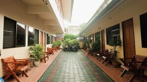 A corridor with wooden benches and potted plants, leading to a building entrance. - Orchid House (Chiang Rai)