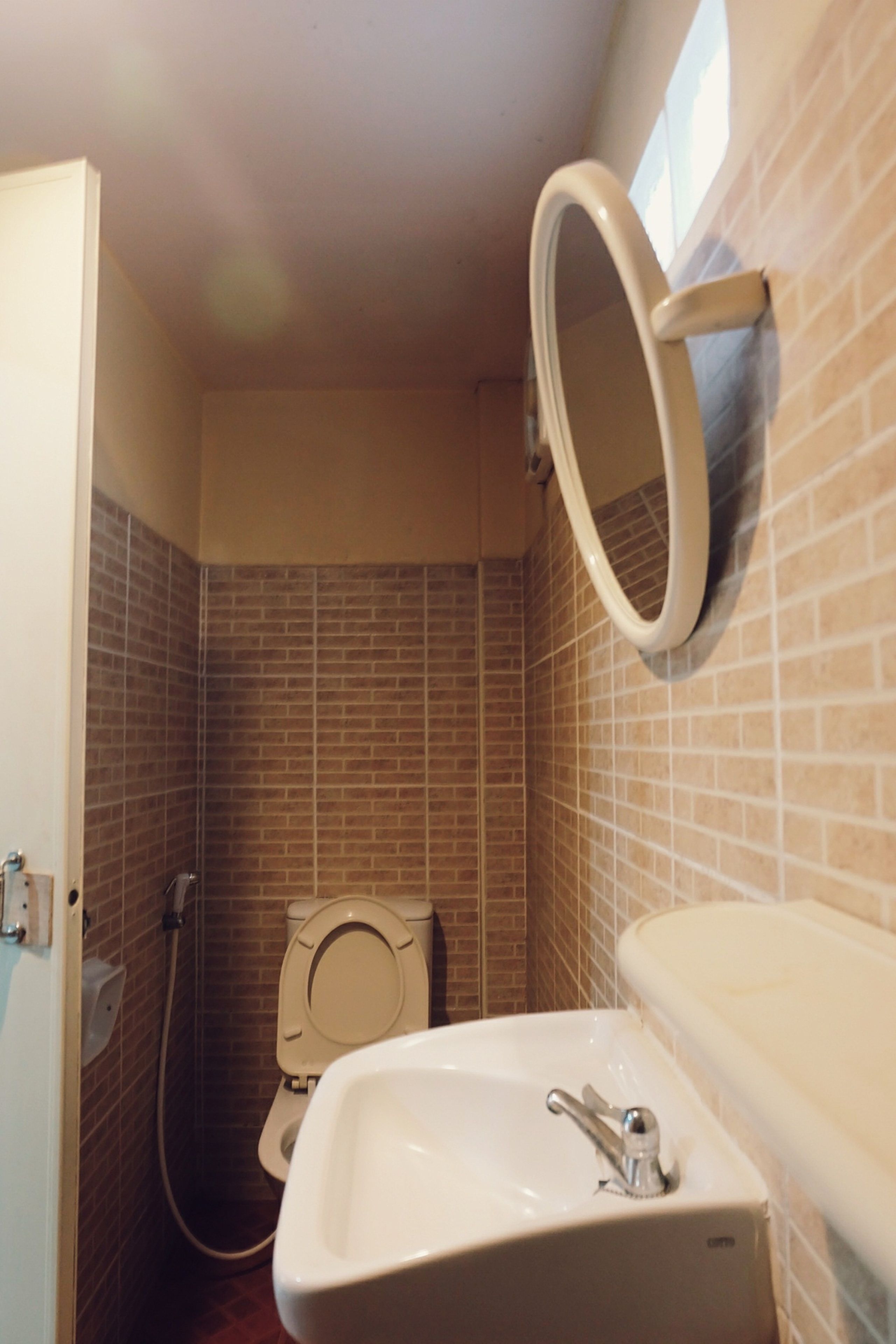A bathroom with a toilet, sink, and a mirror mounted on the wall.