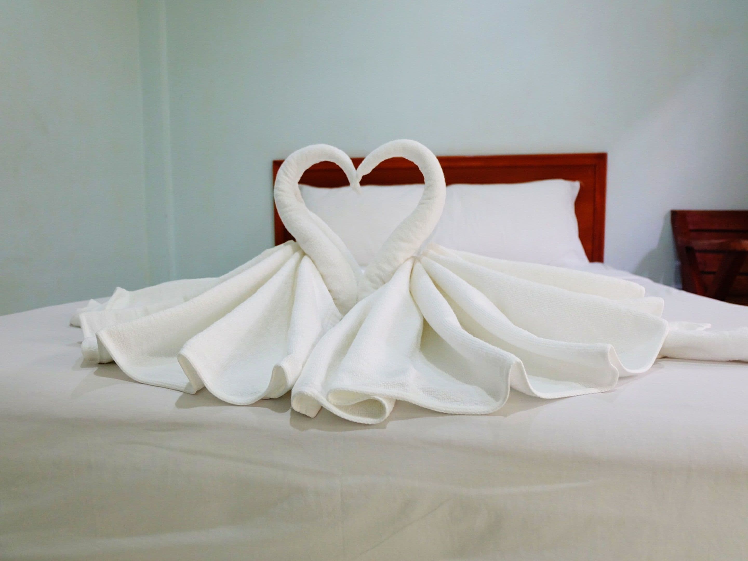 A bed with a heart-shaped towel arrangement.