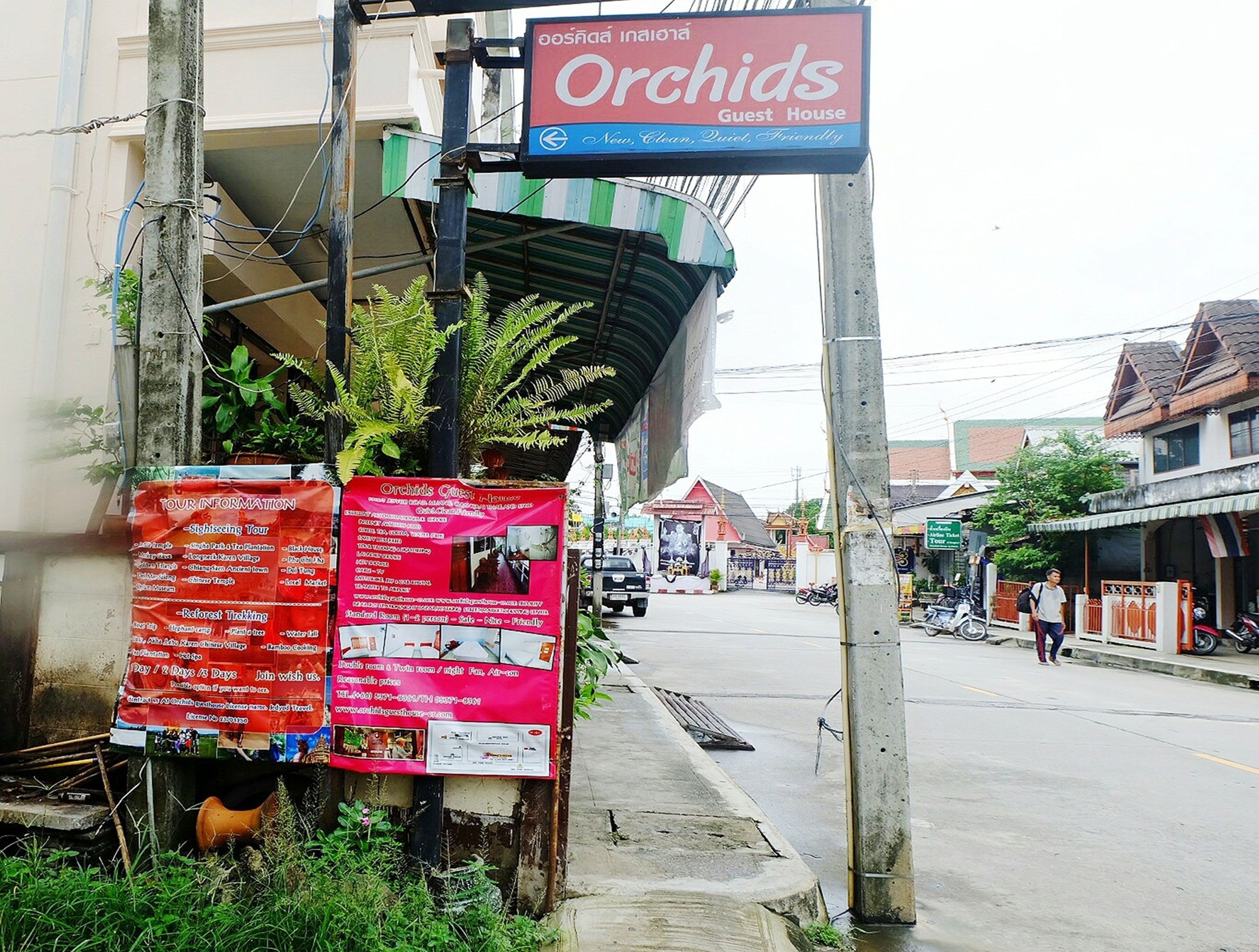 A sign for Orchids Guest House, indicating it is a new, clean, quiet, and friendly establishment.