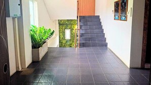 A modern interior with a staircase, a small window, and a wall-mounted picture frame. - Hotel De Ratt (Ratsada)