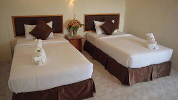 Habitación de hotel con dos camas, cada una con cabecero marrón, ropa de cama blanca y una toalla sobre la cama.