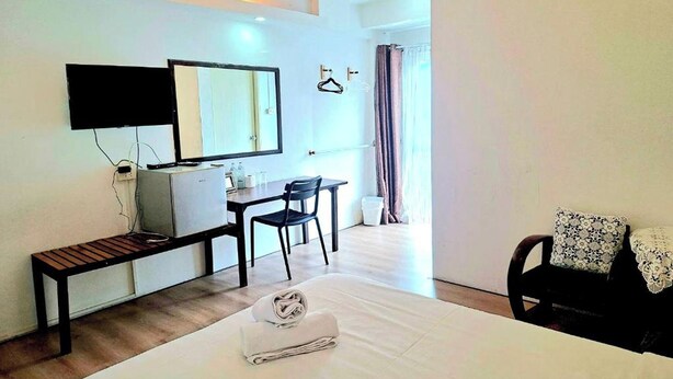 A hotel room with a bed, a desk, a chair, a television, and an air conditioning unit. - Hotel De Ratt (Ratsada)