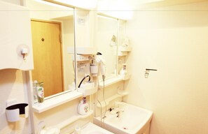A bathroom with a sink, mirror, and various toiletries. - G'inns guest house - Hostel (Tokyo)
