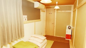 Una habitación pequeña y acogedora con cama, almohadas, una puerta de madera y un calentador.