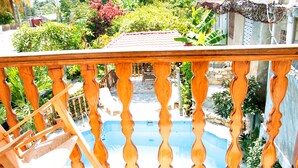 Varanda de madeira com vista para uma piscina e vegetação ao redor.