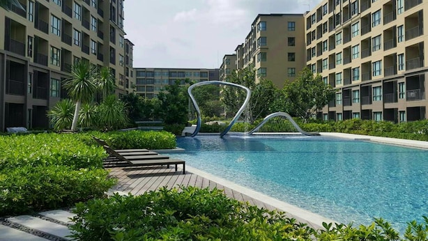 A modern hotel with a swimming pool surrounded by lush greenery and a unique architectural feature in the center. - Rain Cha-am Hua-hin by Noppawan (Cha-am)