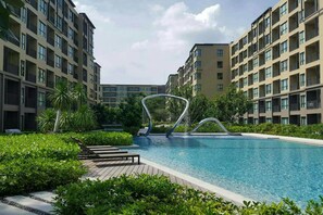 A modern hotel with a swimming pool surrounded by lush greenery and a unique architectural feature in the center.