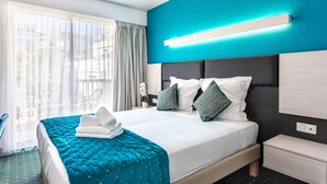A modern hotel room with a large bed, a nightstand, a bedside table, and a view of the outdoors through sheer curtains. - Hotel Jardin Croisette (Cannes)