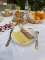 A table set with a plate of sliced cheese, a wrapped ham, and condiments.
