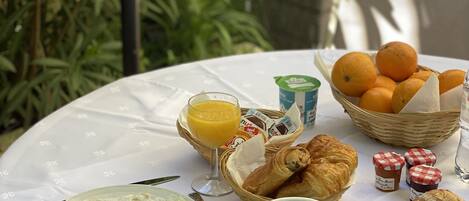 Aamiaispöydällä on munia, paahtoleipää, croissantteja, appelsiinimehua, kahvia ja leivonnaisia.