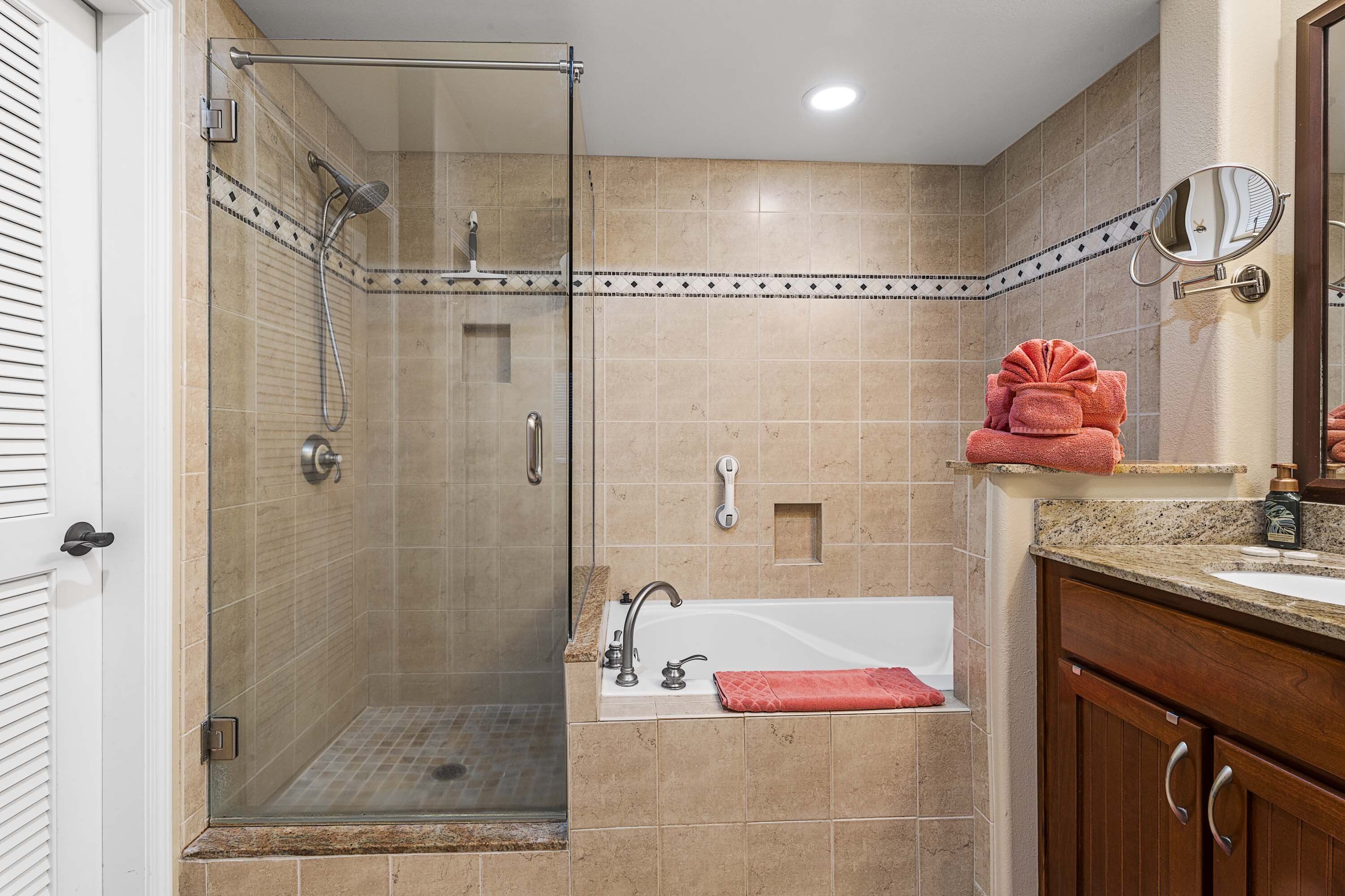 A bathroom with a glass-enclosed shower, a freestanding bathtub, and a vanity with a mirror.