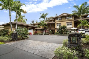 A multi-story hotel with a stone pathway leading to the entrance, palm trees, and a numbered sign indicating the building's location. - Hali'i Kai At Waikoloa 2b 2 Bedroom Condo by RedAwning (Waikoloa)