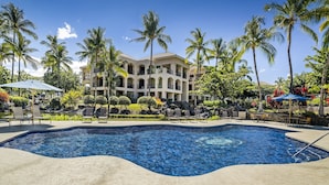 A hotel with a swimming pool, palm trees, and outdoor seating areas.
