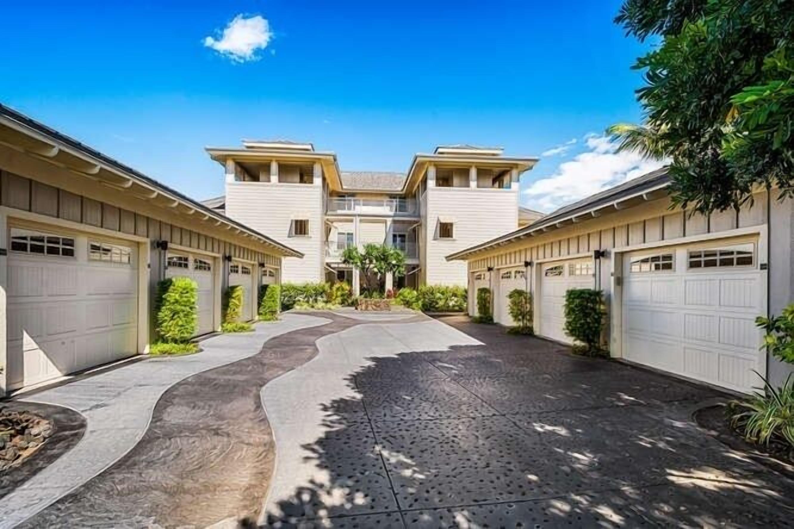 Uma entrada de garagem residencial que leva a uma casa de dois andares, com garagem de cada lado.