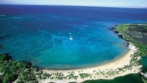 An aerial view of a tropical island with a clear blue sea, a sandy beach, and dense greenery. - Waikoloa Beach S H32 2 Bedroom Condo by RedAwning (Waikoloa)
