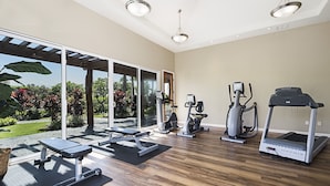 Ein großzügiger Home-Gym-Bereich mit Laufband, Crosstrainer und einer Gewichtbank.