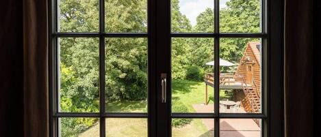 Una ventana con vista a una cabaña de madera y un jardín.