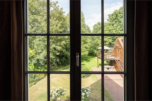 Una ventana con vista a una cabaña de madera y un jardín.