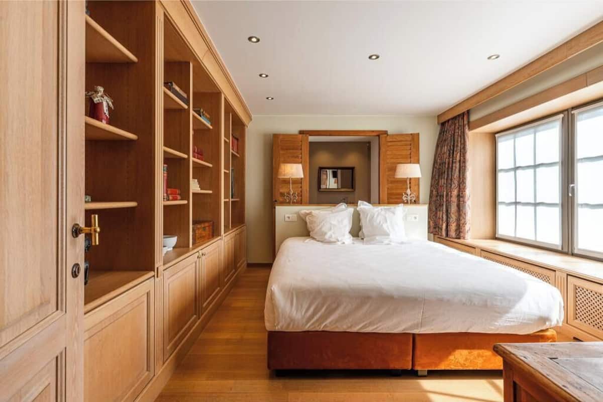 Ein Hotelzimmer mit einem großen Bett, integrierten Holzböden, einem Fenster mit Vorhängen und einem kleinen Tisch.