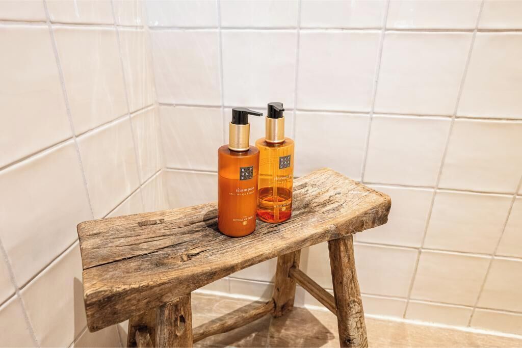A wooden stool with two bottles of shampoo on it.