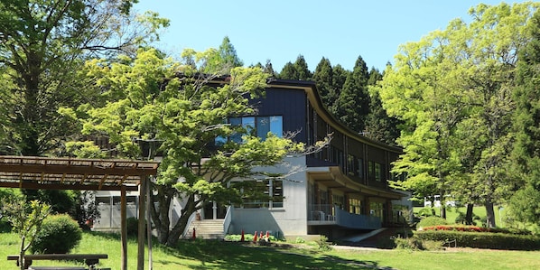 A modern building with a curved facade, surrounded by lush greenery and trees.