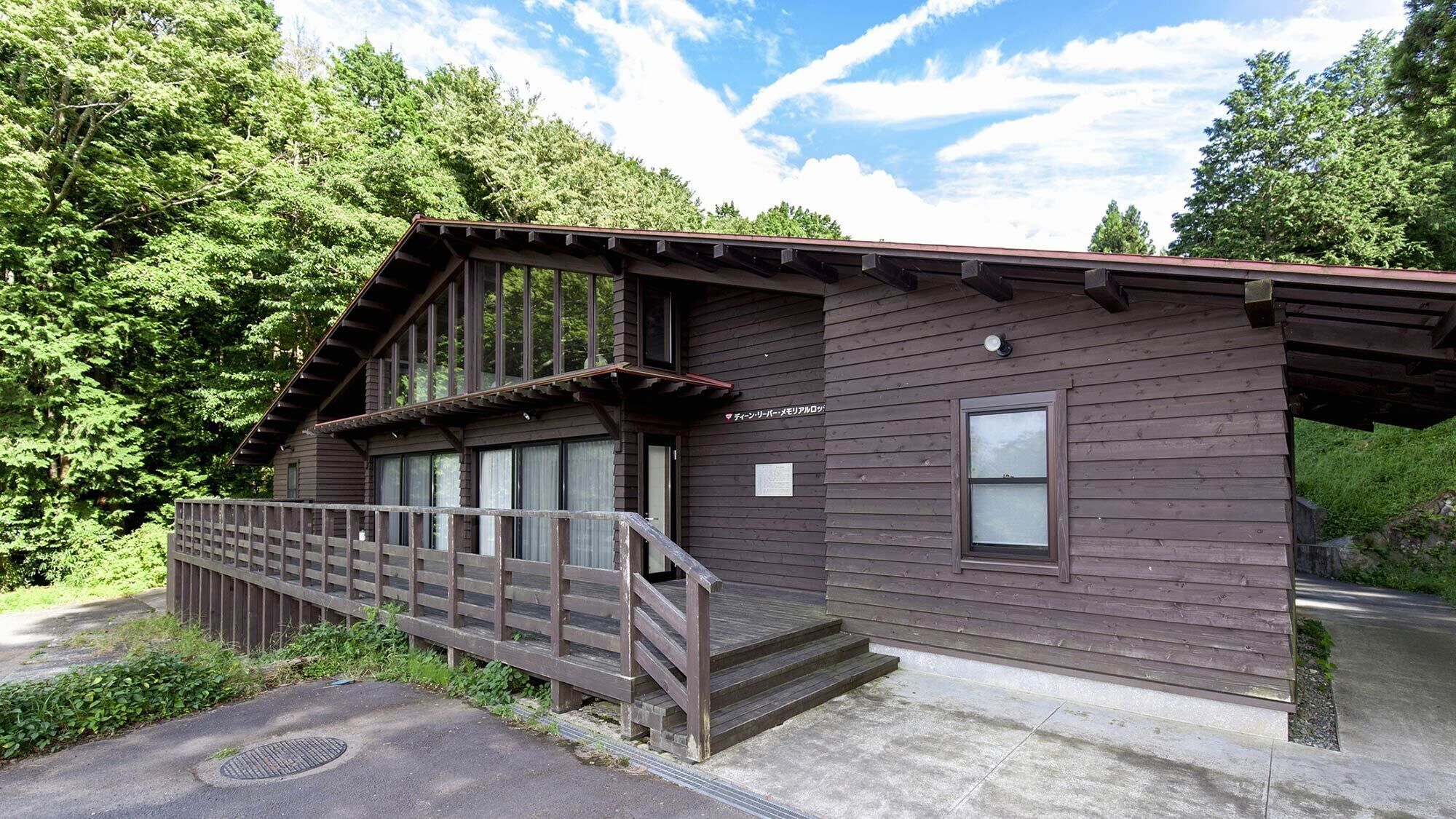 Une cabane en bois avec une véranda, une fenêtre et une enseigne.