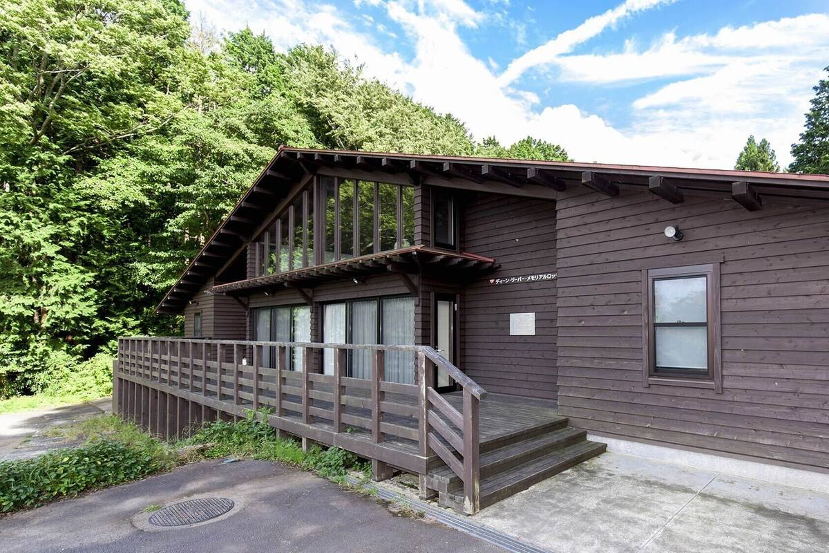 Une cabane en bois avec une véranda, une fenêtre et une enseigne.