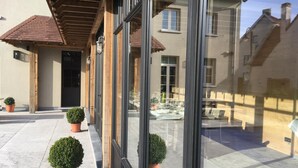 Un edificio moderno con amplios ventanales, un patio cubierto y plantas en macetas.