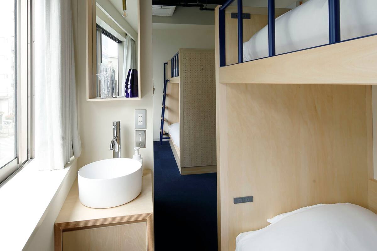 A bunk bed with a wooden headboard, a round white sink, and a mirror above it.