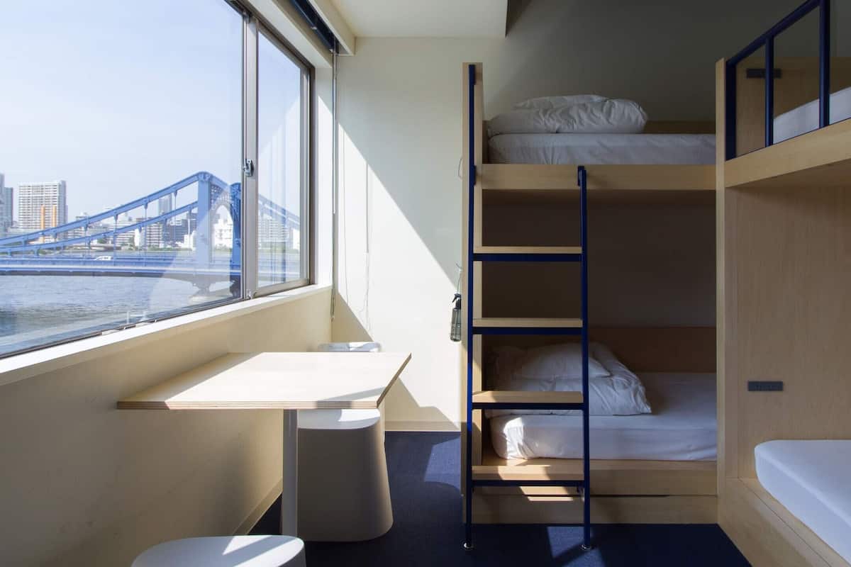 A compact room with bunk beds, a desk, and a window overlooking a bridge.