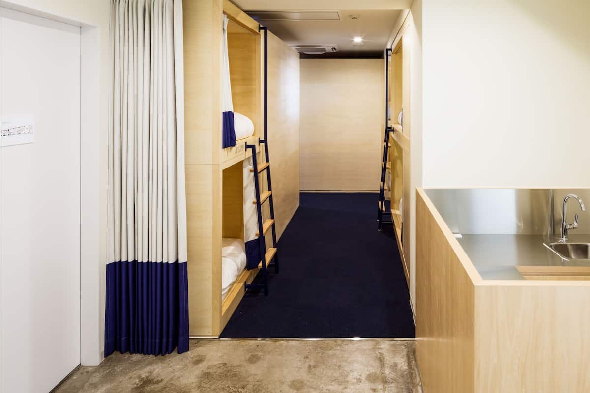 A narrow corridor with bunk beds on one side and a kitchenette on the other.