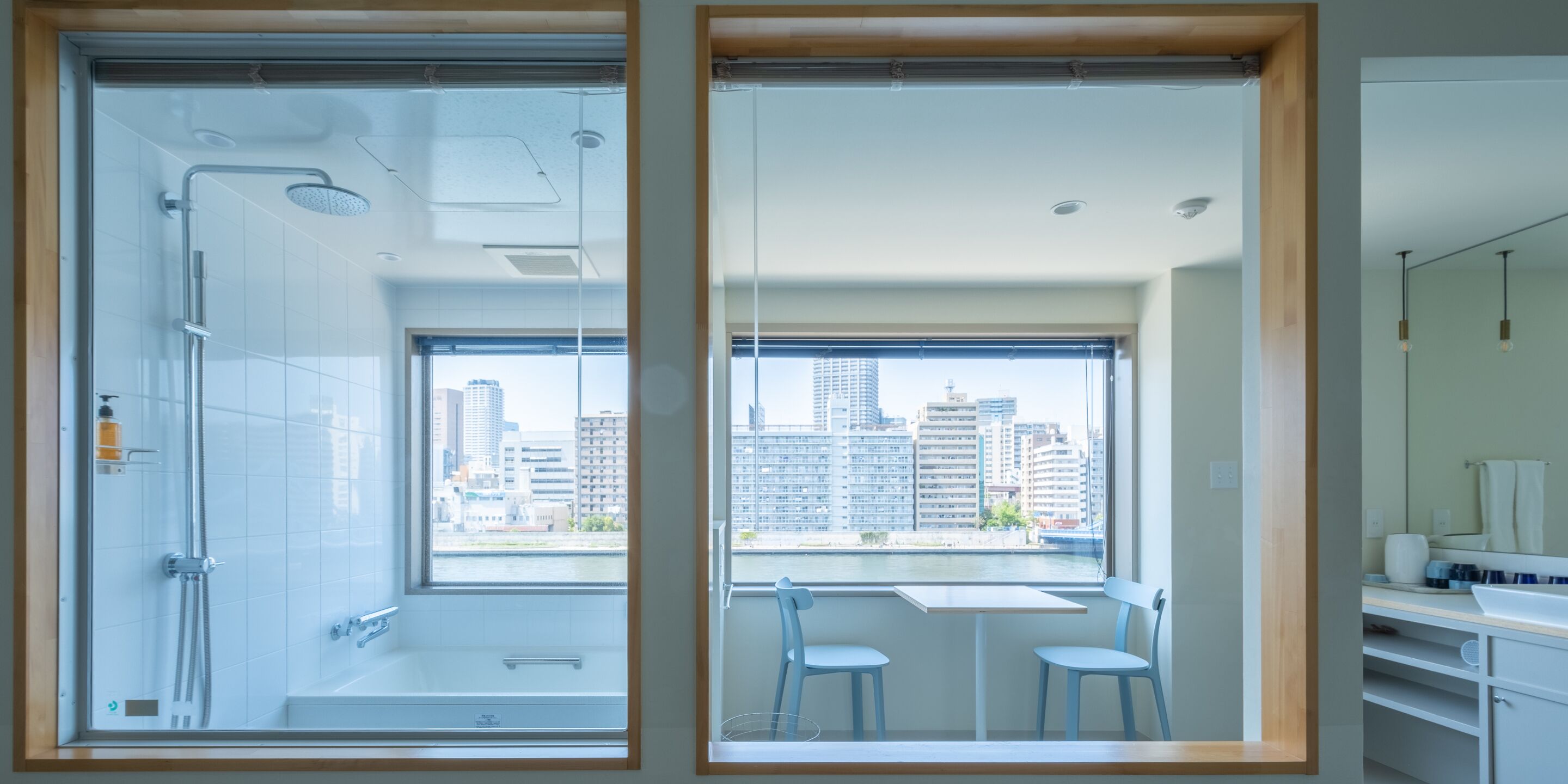 A modern bathroom with a glass shower enclosure, a bathtub, and a window with a city view.