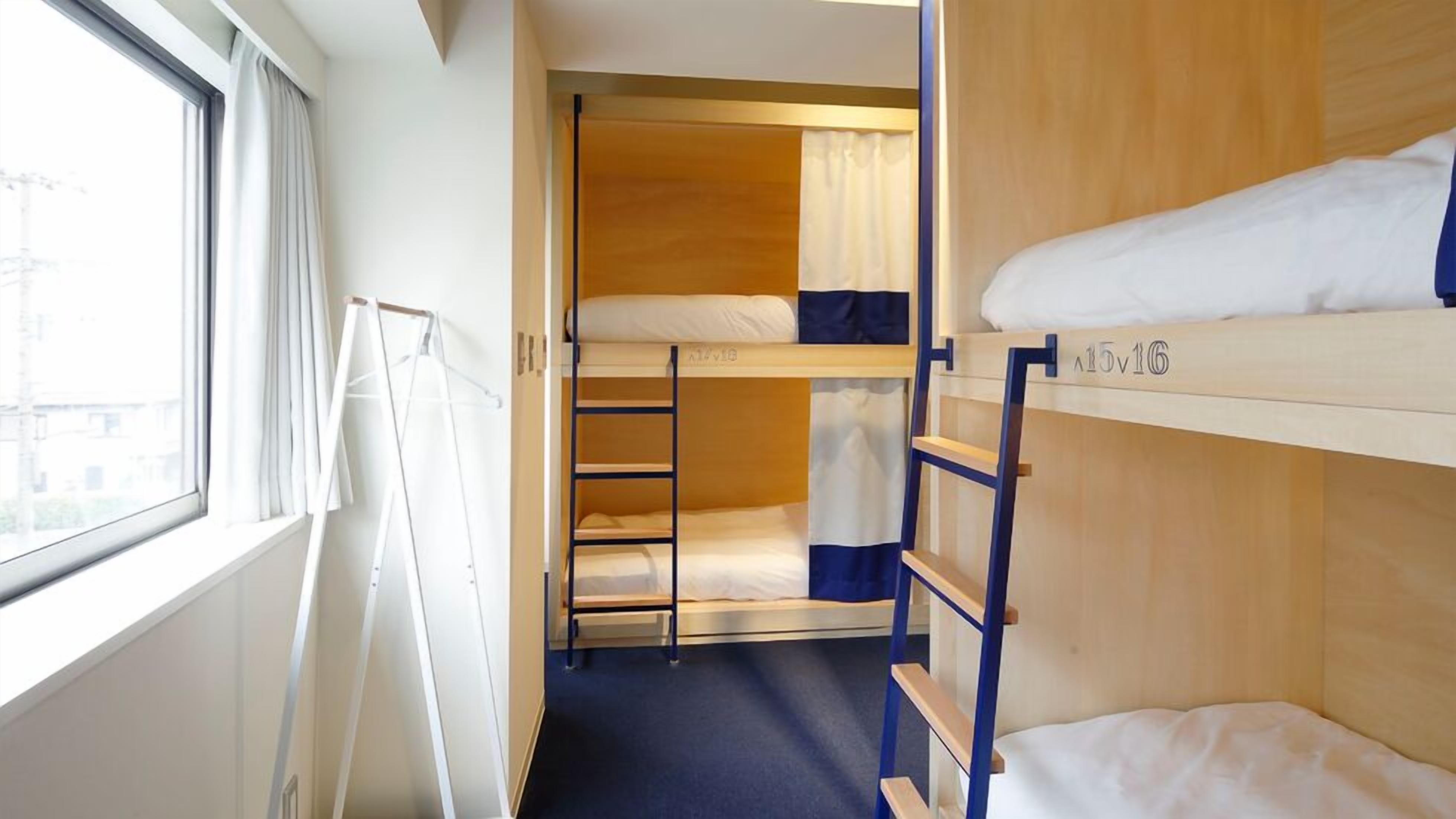 Een slaapkamer met een stapelbed, een raam en uitzicht op gebouwen.