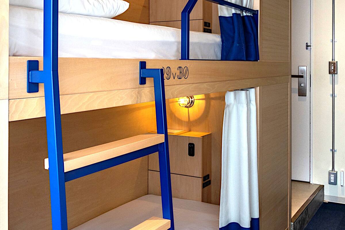 A bunk bed with a wooden frame and a lower shelf, a small drawer, and a door with a handle.